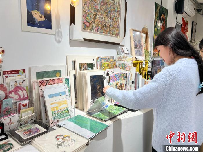 圖為藝術(shù)品商店內(nèi)，顧客挑選插畫作品?！＄婌?攝