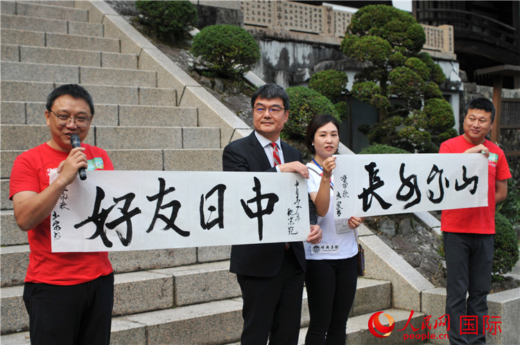 東京中國文化中心主任羅玉泉展示其為本次活動書寫的題詞“中日友好，山高水長”。人民網 蔣曉辰攝