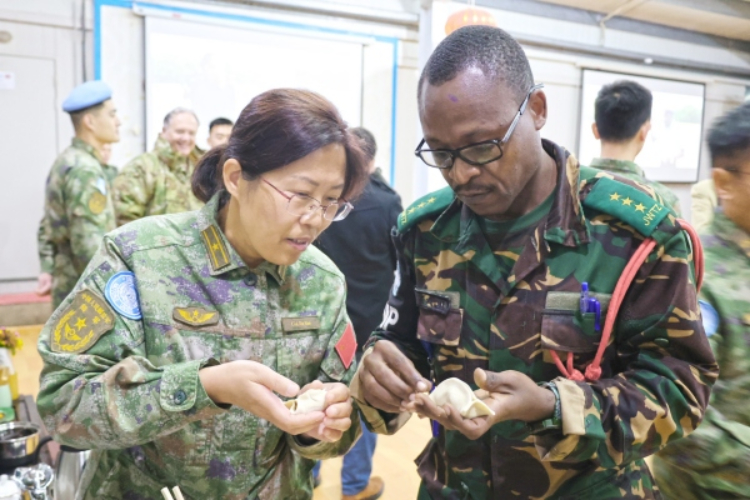 圖為維和官兵與外軍人員共同包餃子。胡光明攝