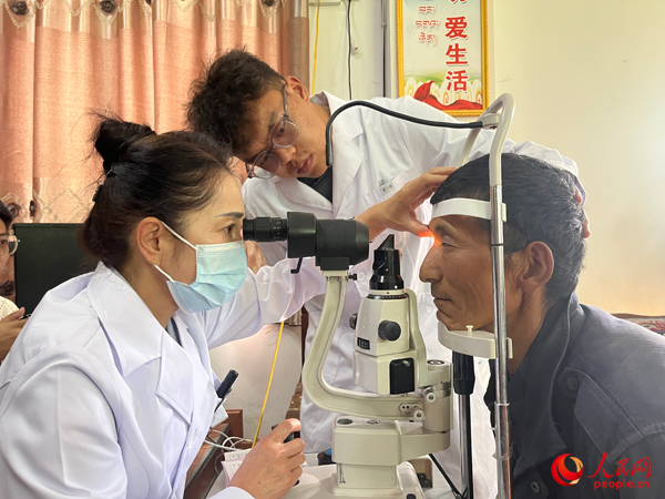 王紅英（左）和團隊成員為達熱村村民檢查眼睛。人民網(wǎng)記者 杜燕飛攝
