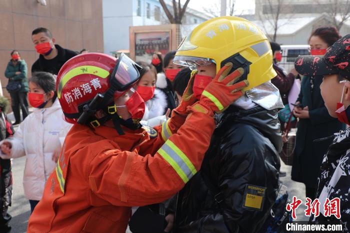 圖為小朋友體驗(yàn)試穿消防滅火防護(hù)服。　楊龍建 攝