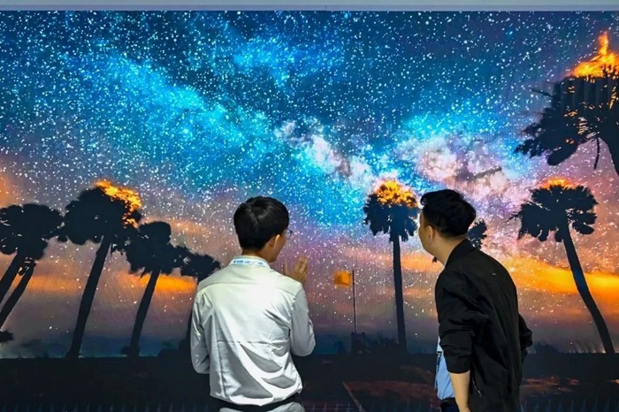 長春光博會希達電子展區(qū)，一位工作人員正在給一位觀眾講解。（長春新區(qū)供圖）