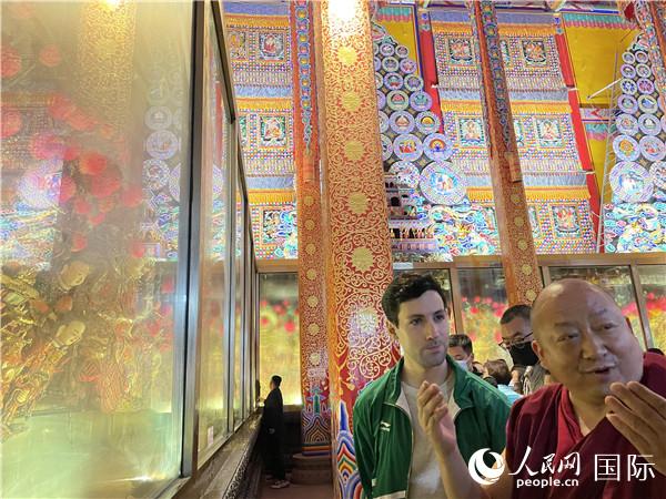7月25日，省級(jí)非物質(zhì)文化遺產(chǎn)項(xiàng)目塔爾寺酥油花的代表性傳承人朋措堅(jiān)參（右）在塔爾寺酥油花館講解酥油花的制作過程。人民網(wǎng) 謝瑩攝