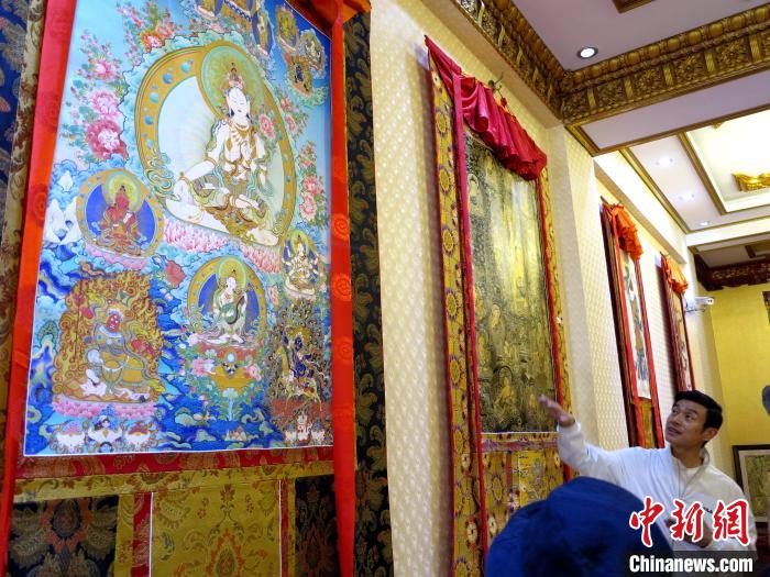圖為完德尖措展示熱貢龍樹(shù)畫(huà)苑內(nèi)的唐卡?！?zhí)砀?攝