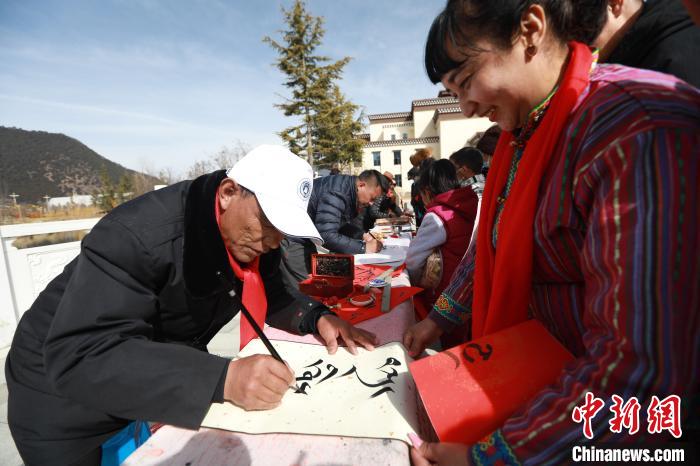 圖為林芝市文聯(lián)書法家協(xié)會(huì)會(huì)員向民眾贈(zèng)送藏文書法作品?！埩?攝