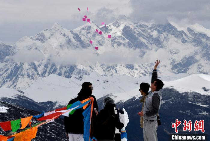 圖為5月14日，游客在西藏林芝色季拉山觀景臺(tái)拋灑“隆達(dá)”(風(fēng)馬旗，藏族民眾的一種祈福方式)。　李林 攝